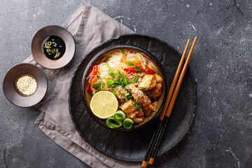 A bowl of glass or cellophane noodles with Asian caramelized chicken breast on dark grey background top view copy space for text