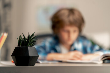 close up in the children's room a schoolboy in white sweater and a blue checkered shirt lies on a...