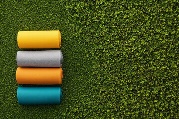 Colorful yoga mats arranged on lush green grass, inspiring fitness and relaxation.