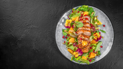 duck breast fried and salad leaves on plate on a dark background. top view. copy space for text