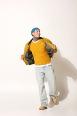 A young man confidently poses in a stylish outfit, highlighting his tattoos and vibrant colors.