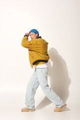 The young man showcases his unique tattoos while striking a vibrant pose in relaxed clothing.