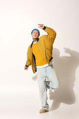 A youthful man adorned with tattoos joyfully dances, showcasing a colorful outfit.