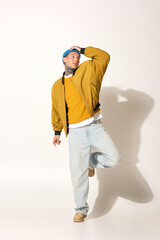 A young man showcases his tattoos while striking an artistic pose in casual attire.