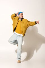 A young man in a vibrant outfit is energetically dancing, expressing joy and creativity.
