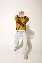 A young man with vibrant tattoos strikes a playful pose while wearing a colorful jacket.