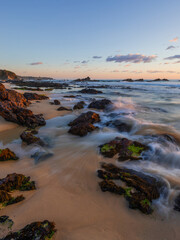 Obraz premium Water flows between rocks on the sandy shore.