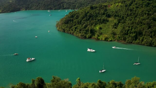 Aerial view of Praia Vermelha with serene boats and lush forest along the coastline, Paraty, Brazil.