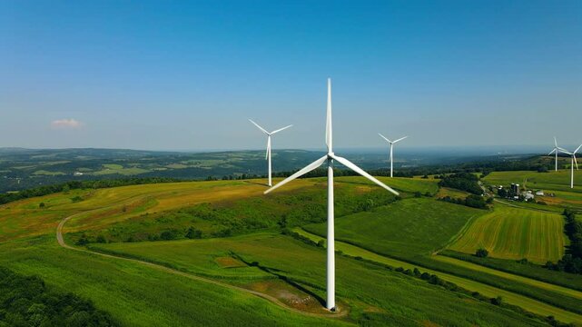 Aerial view of a scenic wind farm with windmills and lush farmland under a sunny sky, Lowville, United States of America.