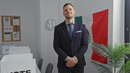 Smiling hispanic man in suit standing in a voting room with mexican flag, portraying electoral...