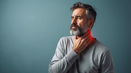 Fototapeta premium Middle-aged man suffering from throat issues, grabbing his neck and showing signs of pain.