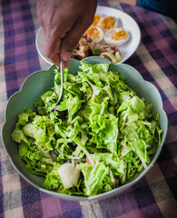 Green salad close-up of man preparing green salad in a bowl.