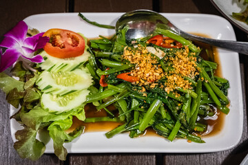 Stir-fried Water Spinach on white plate. Stir Fried Sliced Morning Glory with oyster sauce, chili and garlic