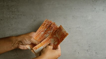 Hands holding multiple philippine pesos against a concrete background showcasing filipino currency...