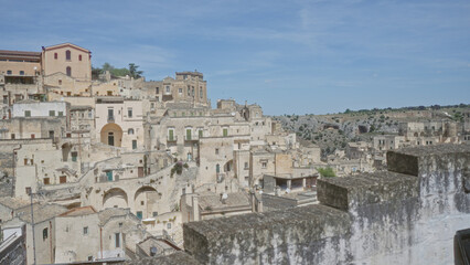 Historic townscape of matera, basilicata, italy showcasing ancient stone buildings nestled on a hillside under a bright blue sky.