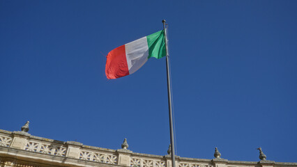 The italian flag flutters against a clear blue sky above a historic building in lecce, puglia, italy, showcasing a vivid scene in the heart of this charming european town.