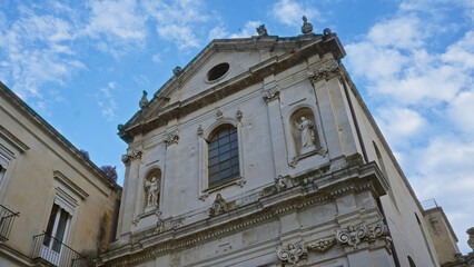 A stunning historical building facade with intricate stone carvings and statues under a bright blue sky in lecce, puglia, italy, showcasing european architectural beauty.