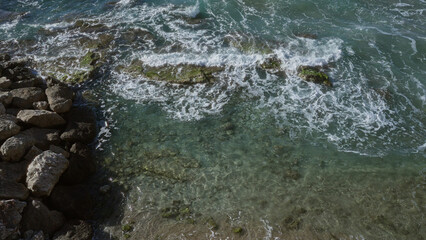 Rocky shoreline with clear turquoise water and foamy waves in gallipoli, puglia, salento, italy, showcasing a scenic coastal landscape with natural beauty.