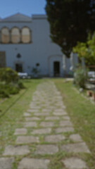 Pathway leading to historic building in puglia, italy with greenery on both sides during a sunny day, showcasing european architecture and serene outdoor setting