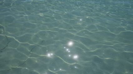Sparkling sunlight reflects on the clear shallow water of the mediterranean sea in porto cesareo, italy, showcasing the serene and tranquil beauty of the salento coast in puglia