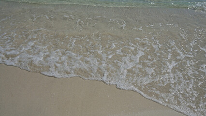 Calm, clear waves gently lap on the sandy shore of porto cesareo in salento, puglia, italy, offering a serene beach setting perfect for relaxation and summer tourism.