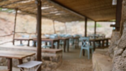 Defocused outdoor patio cafe in mallorca spain with empty tables and chairs under wooden pergola creating a blurred bokeh background image