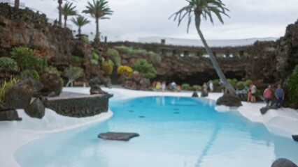 Defocused view of outdoor pool area in lanzarote, spain, with blurred people in the background enjoying the tranquil environment of the canary islands.