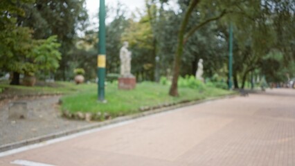 Blurred view of a defocused street with trees and statues in la spezia, italy, capturing a serene autumn ambiance with bokeh effects in a european town setting.