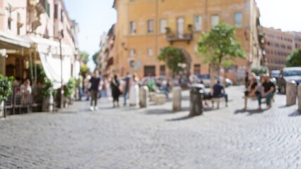 Blurred people strolling on a sunny cobblestone street in rome, italy, with a historic, vibrant atmosphere and outdoor cafes in the charming old town.