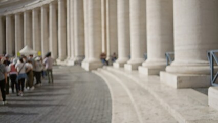 Blurred crowd with columns in vatican city depicting people visiting italy with an out-of-focus background and architectural serenity during a sunny day.