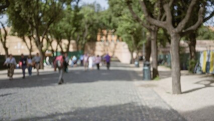 Blurred scene with people walking in old town rome street, featuring defocused trees and urban greenery in italy outdoors.
