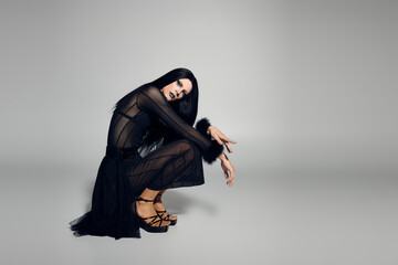 A confident drag queen poses in an elegant black outfit with a modern twist, exuding bold energy.
