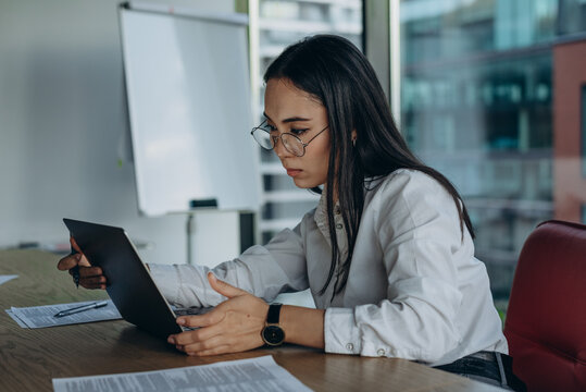 Asian financial analysist  staying late in office, controls commercial data at workplace