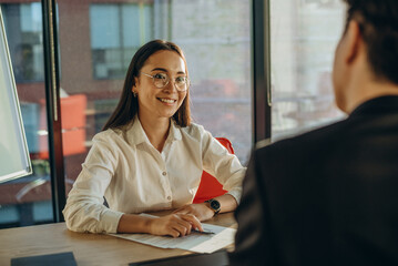 Business professionals discuss contract details sitting at table at sunset light