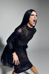 A stylishly dressed drag queen embodies fierce expression and creativity in a studio setting.
