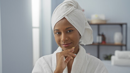 Young woman with a towel on her head smiling in a spa room, exuding beauty and relaxation.