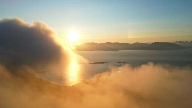 Aerial view of serene mountains under the midnight sun with clouds and tranquil water, Hanoy, Norway.