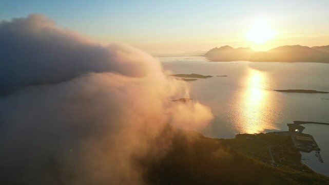 Aerial view of serene midnight sun illuminating majestic mountains and tranquil waters with clouds, Hanoy, Norway.