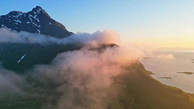 Aerial view of majestic mountains under midnight sun with dramatic clouds, Hanoy, Norway.