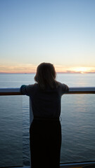 Fototapeta premium Woman standing on cruise ship at sunset overlooking ocean horizon embracing tranquility and adventure displaying youthful beauty and serenity outdoors on dock