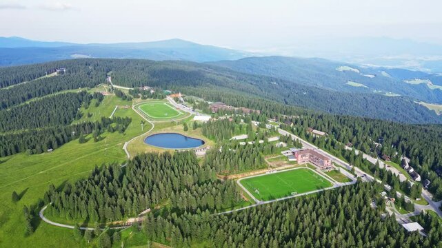 Aerial view of a beautiful mountain resort surrounded by lush green forests and a serene lake, Rogla, Slovenia.