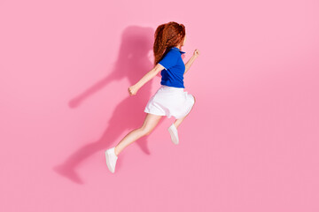 Full length photo of adorable lovely girl wear short skirt jumping high running empty space isolated pink color background