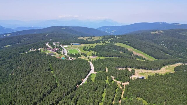 Aerial view of serene mountainous landscape with lush forest and winding road, Rogla, Slovenia.