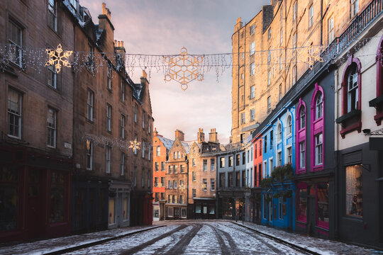 Victoria Street in Edinburgh, Scotland adorned with festive Christmas string lights and fresh snowfall, showcasing the charm of the old town during the winter season.