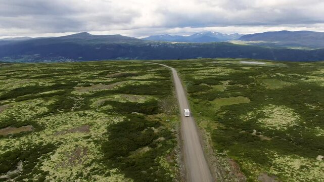 Aerial view of a serene road with a camper driving through beautiful mountainous landscape, Lora, Norway.