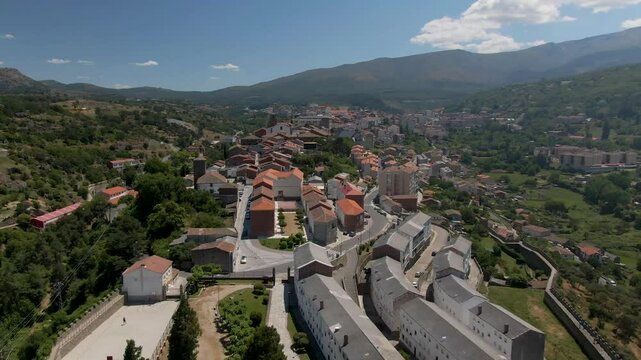 Aerial view of a picturesque hilltop village with traditional stone rooftops surrounded by mountains and greenery, Bejar, Spain.