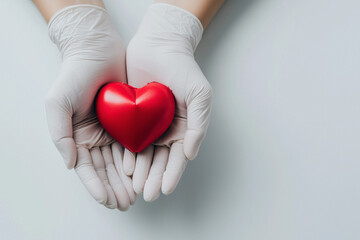 Fototapeta premium two white latex gloved hands gently holding a red heart, symbolizing care, compassion and medical support, emphasizing themes of health, empathy and dedication within a clean, minimalist environment.