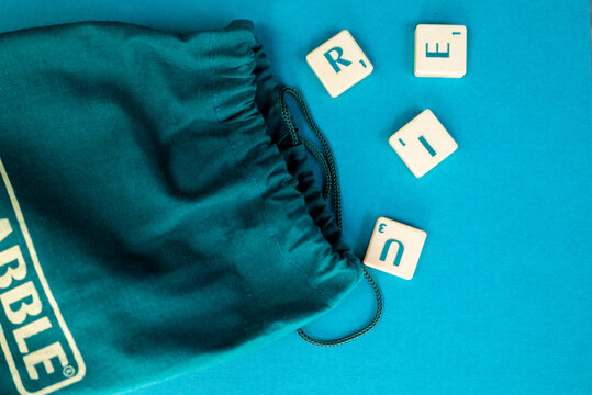 old scrabble board game with letter tiles and green bag