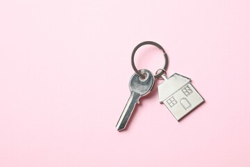 Metallic key with keychain in shape of house on color background