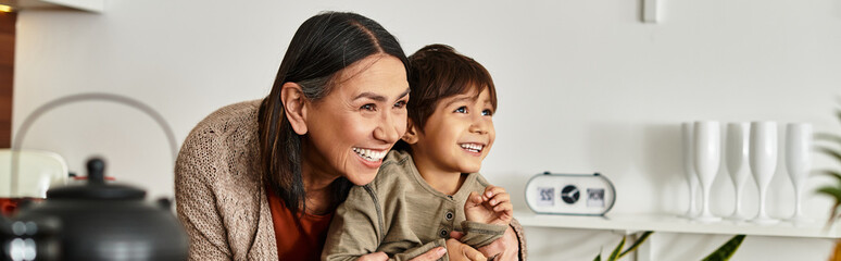 A cheerful asian grandmother and grandson gathers in their stylish kitchen filled with laughter and joy.